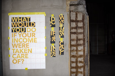 Riesiges Poster auf einem Platz, von oben fotografiert: What would you do if
            your income were taken care of?
